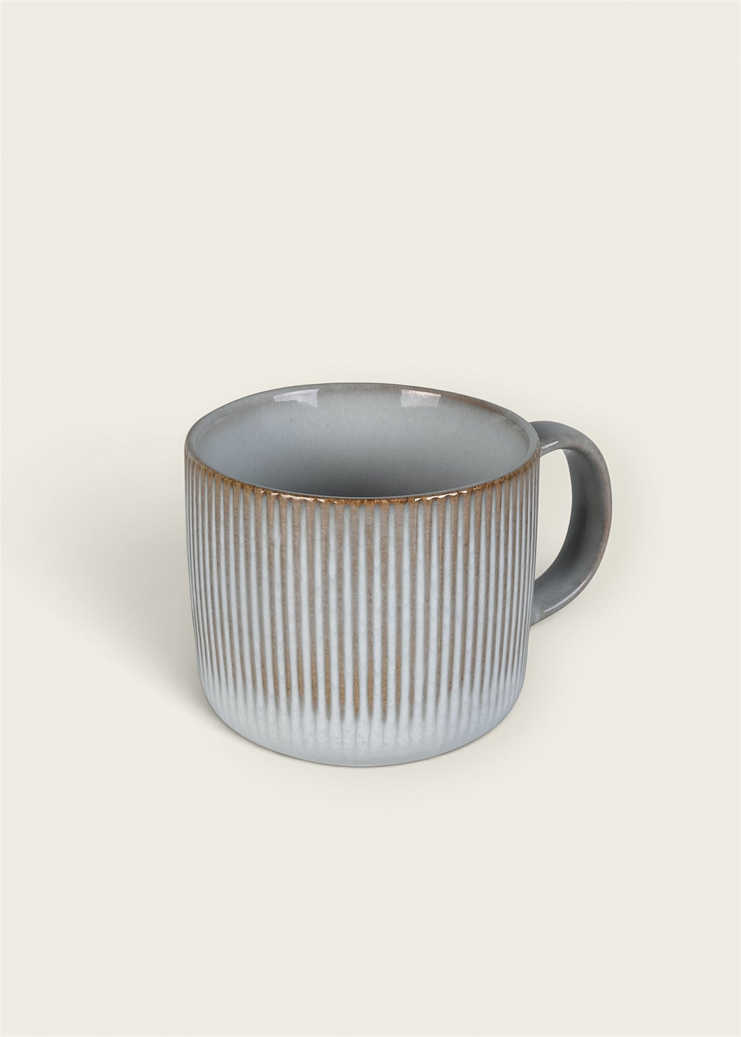 A ceramic mug with a ribbed vertical texture, featuring a light gray exterior that fades to white near the base, accented with a rustic brown glaze around the rim, and a dark gray handle 