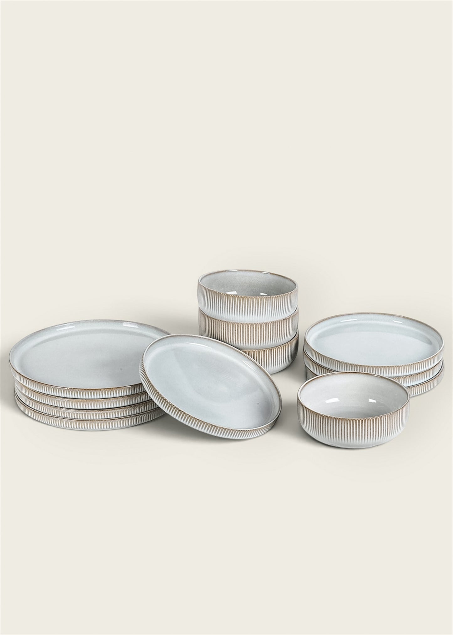 A set of ceramic tableware including plates and bowls with a white glazed centre and ribbed beige rims.