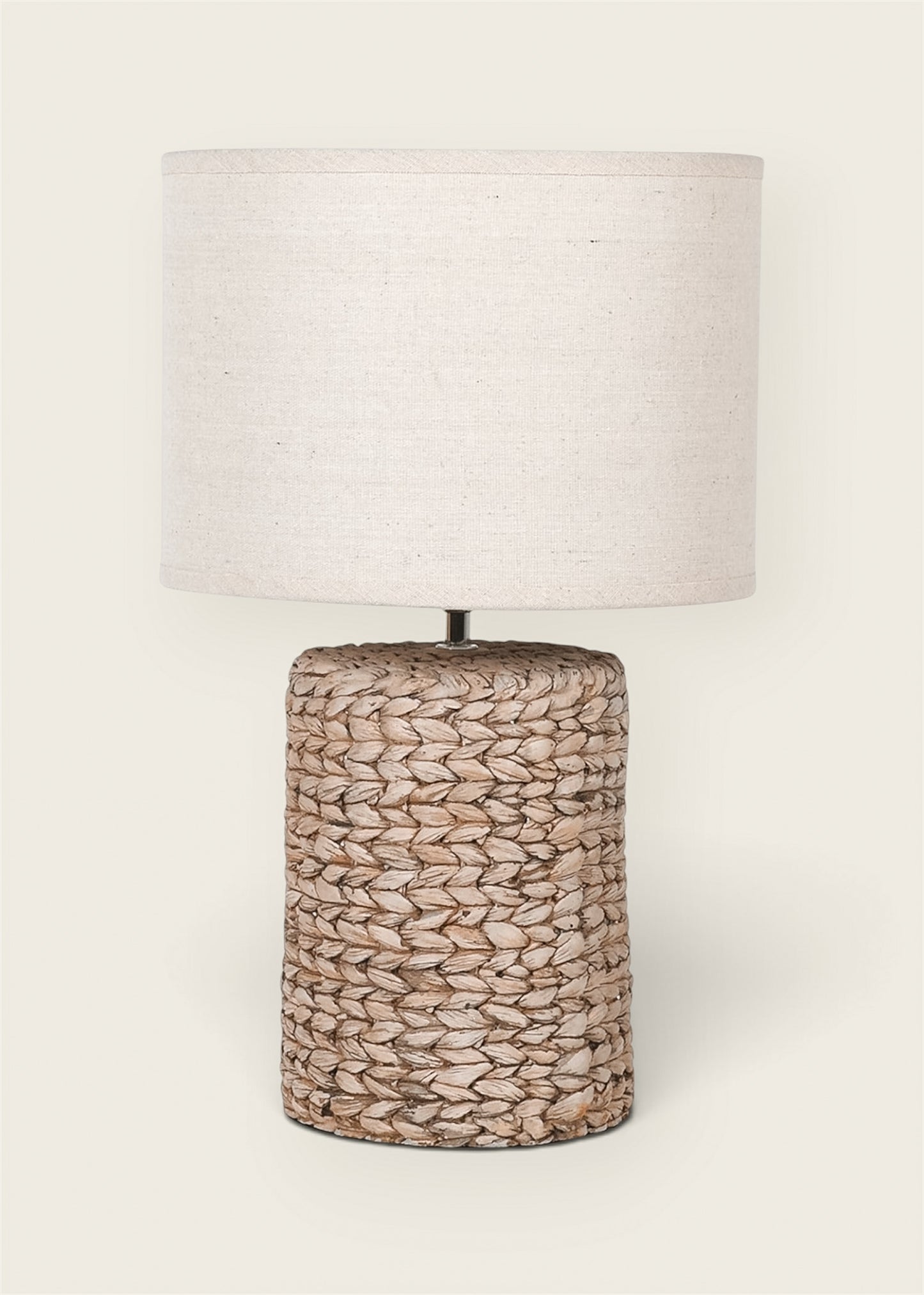 A table lamp with a cylindrical woven natural fiber effect base and a matching drum shade made of textured off-white fabric