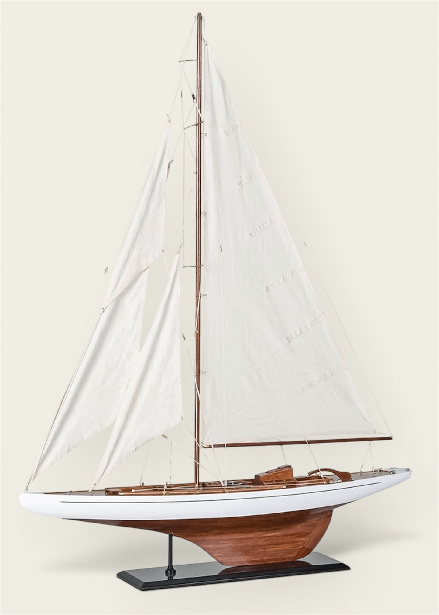 A decorative wooden model sailboat with white sails, a white hull, a brown wooden base, and a black display stand.