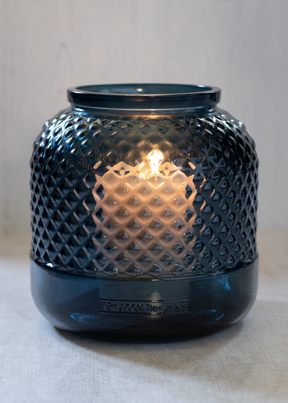 A coastal-style candle holder/ vase made from 100% recycled glass in a rich petrol blue colour: Handcrafted in Spain, featuring a diamond-textured surface-ideal for candles or seasonal floral arrangements